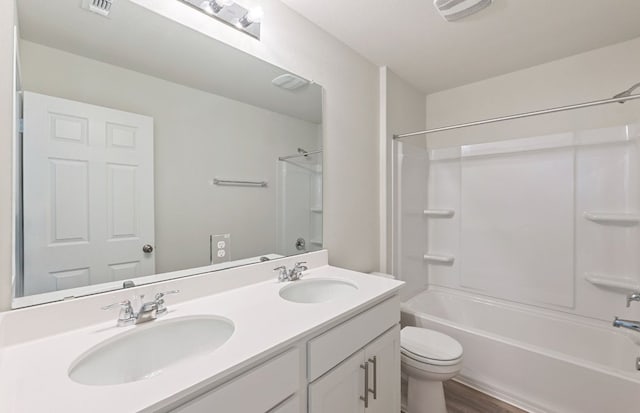 bathroom with toilet, wood finished floors, double vanity, and washtub / shower combination