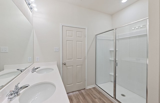 bathroom with a shower stall, wood finished floors, and double vanity