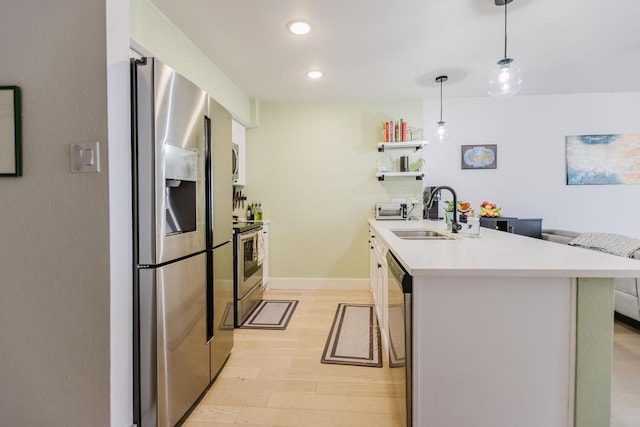 909 Reinli St Unit 102, Austin, TX 78751 - kitchen featuring appliances with stainless steel finishes, a peninsula, light wood-style floors, light countertops, and decorative light fixtures