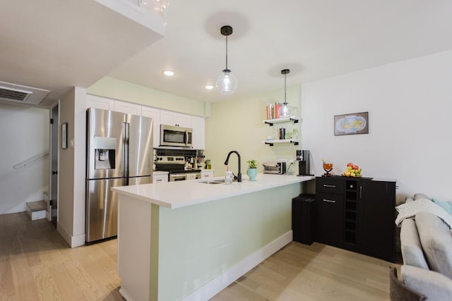 909 Reinli St Unit 102, Austin, TX 78751 - kitchen with appliances with stainless steel finishes, a peninsula, light wood-type flooring, white cabinets, and recessed lighting