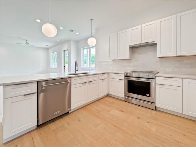 3614 Abbate Cir Unit B, Austin, TX 78721 - kitchen featuring appliances with stainless steel finishes, a sink, light countertops, white cabinets, and light wood-type flooring