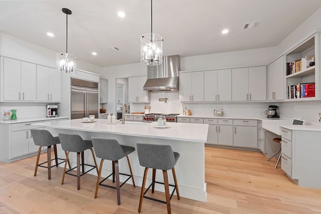 1769 Parten Ranch Pkwy, Austin, TX 78737 - kitchen with stainless steel built in refrigerator, wall chimney exhaust hood, backsplash, a kitchen breakfast bar, and recessed lighting