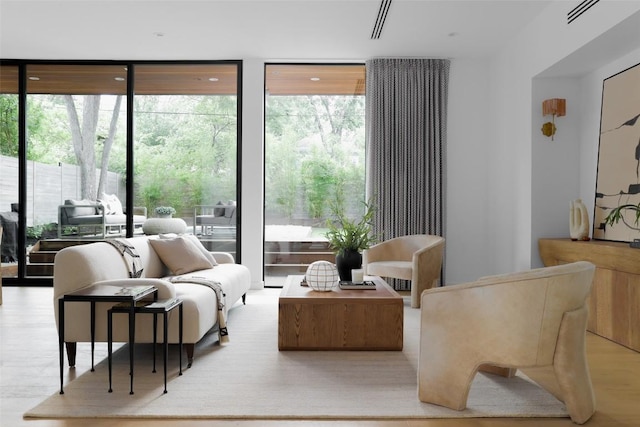 living area with plenty of natural light, a wall of windows, and wood finished floors