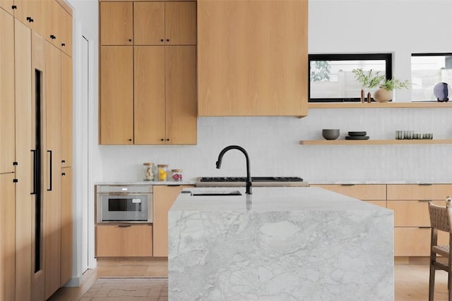 kitchen featuring modern cabinets, light stone countertops, a sink, and stainless steel oven