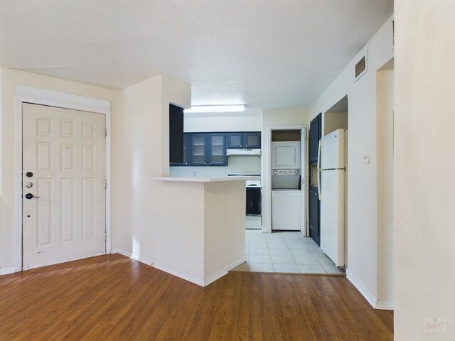 2450 Wickersham Ln Unit 702, Austin, TX 78741 - kitchen with stacked washer / dryer, white appliances, a peninsula, under cabinet range hood, and light countertops