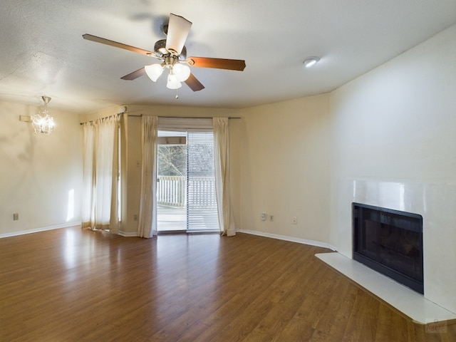 2450 Wickersham Ln Unit 702, Austin, TX 78741 - unfurnished living room with a fireplace, a chandelier, baseboards, wood finished floors, and a ceiling fan