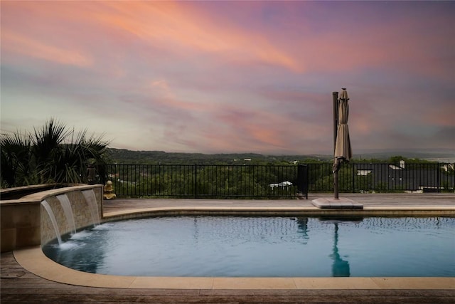 pool at dusk featuring fence