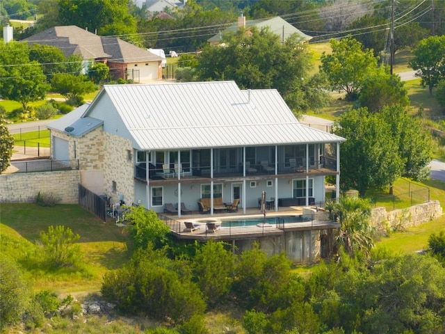 back of house with metal roof, a patio area, a standing seam roof, and a balcony