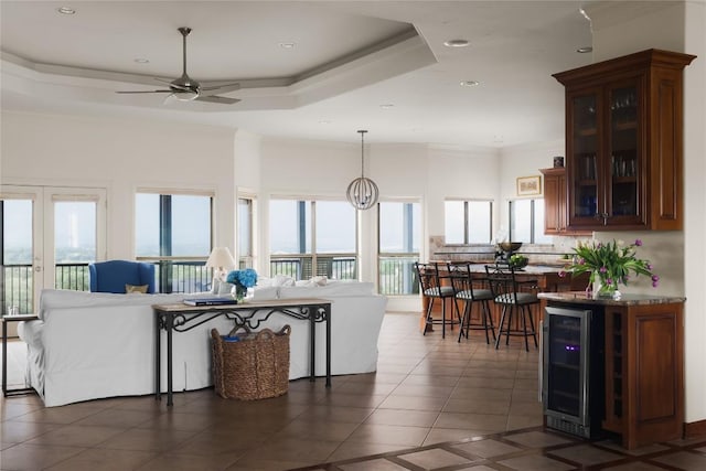 living area featuring beverage cooler, crown molding, dark tile patterned floors, ceiling fan, and plenty of natural light