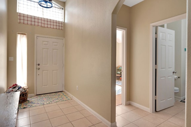 213 Sapphire Ln, Jarrell, TX 76537 - foyer with arched walkways, light tile patterned flooring, baseboards, and a towering ceiling