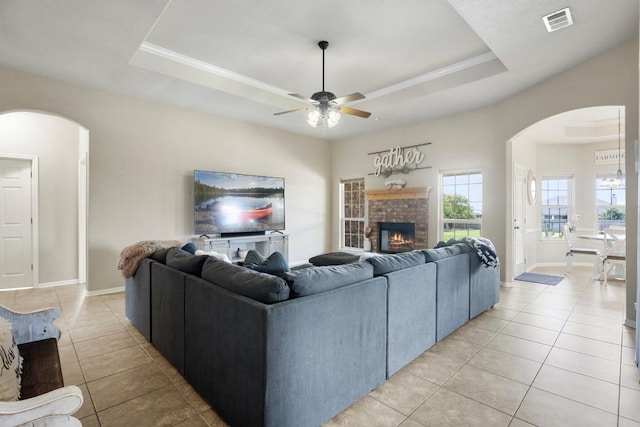 3585 W Amity Rd, Salado, TX 76571 - living room featuring arched walkways, a tray ceiling, light tile patterned floors, a ceiling fan, and ornamental molding
