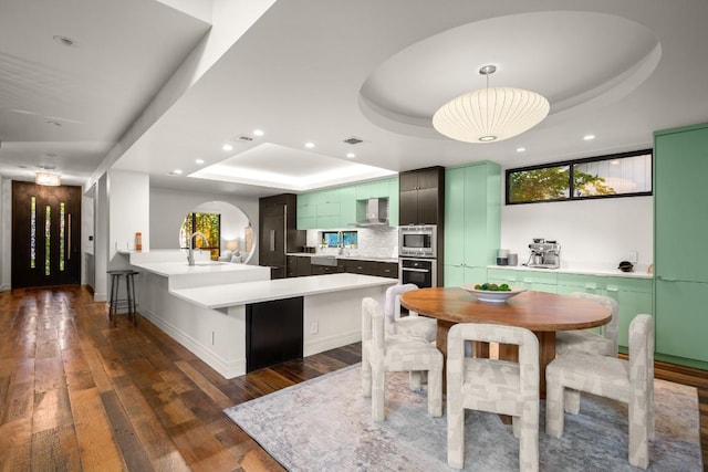 1705 Collier St, Austin, TX 78704 - kitchen with a tray ceiling, stainless steel microwave, green cabinets, black oven, and dark wood-type flooring