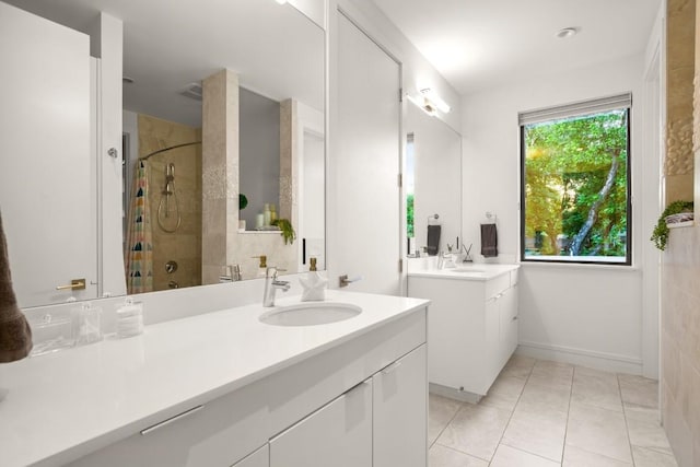 full bath featuring a tile shower, tile patterned flooring, two vanities, and baseboards