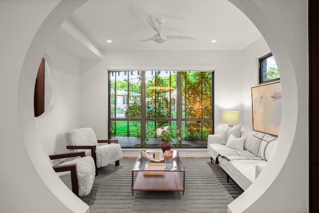 living area featuring arched walkways, a ceiling fan, and recessed lighting