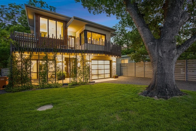 rear view of house featuring an attached garage, driveway, and a balcony
