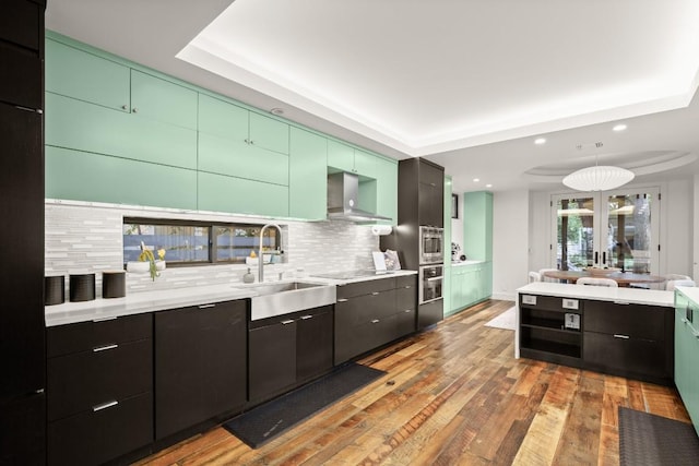 kitchen with a sink, wall chimney range hood, recessed lighting, tasteful backsplash, and light countertops