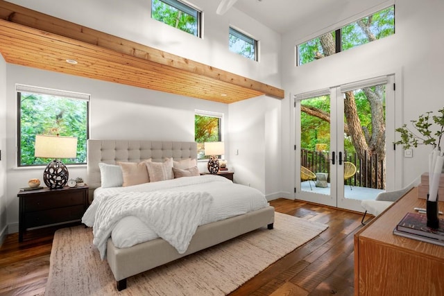 bedroom with access to exterior, a high ceiling, hardwood / wood-style flooring, baseboards, and french doors