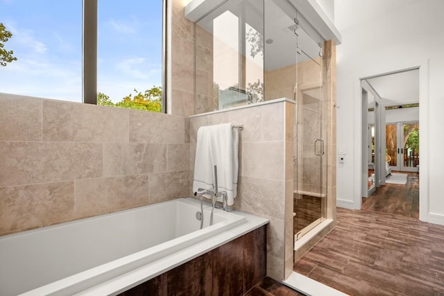 bathroom with a stall shower, a garden tub, and wood finished floors