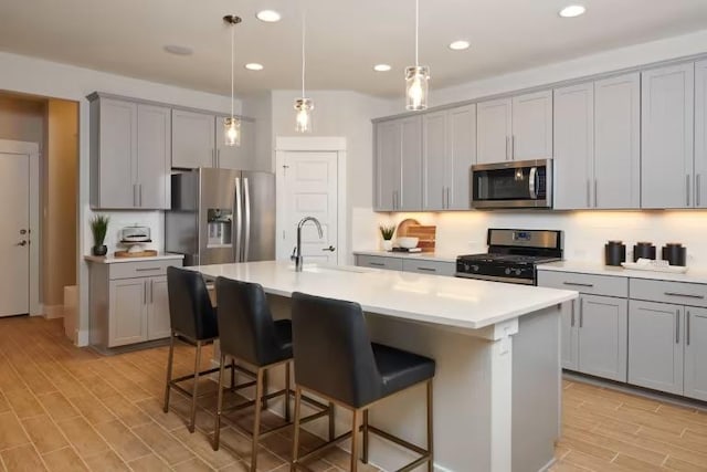 kitchen featuring appliances with stainless steel finishes, gray cabinetry, a breakfast bar, and recessed lighting