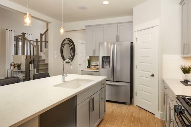 kitchen featuring stainless steel appliances, a sink, gray cabinets, light countertops, and recessed lighting