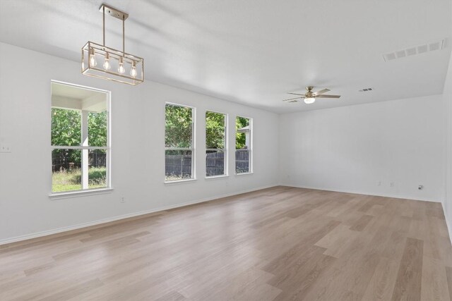 1816 Melissa Oaks Ln, Austin, TX 78744 - spare room featuring plenty of natural light, light wood finished floors, a ceiling fan, and a chandelier