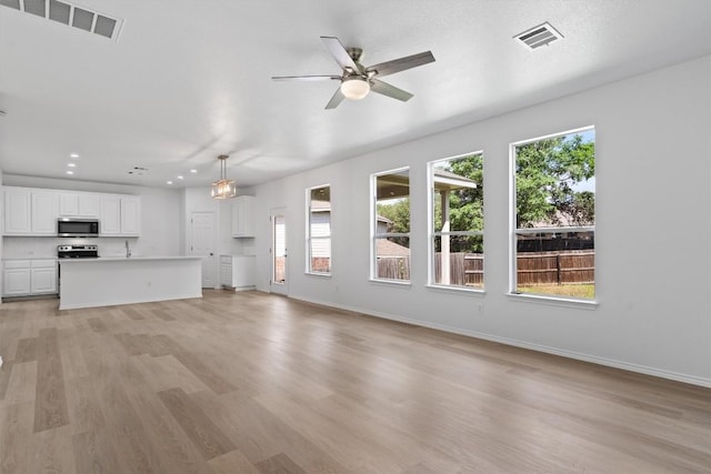 1816 Melissa Oaks Ln, Austin, TX 78744 - unfurnished living room featuring healthy amount of natural light, light wood finished floors, a ceiling fan, baseboards, and recessed lighting