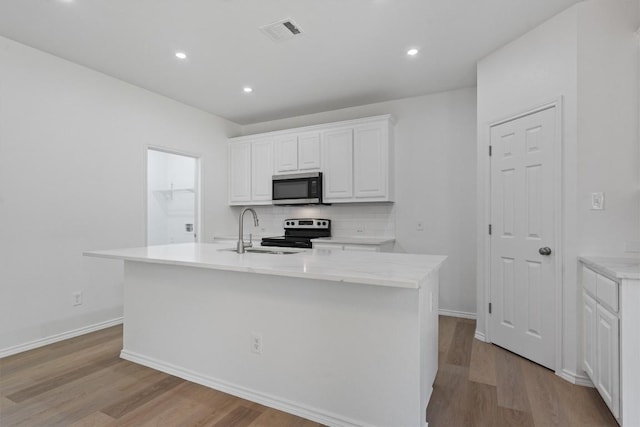 1816 Melissa Oaks Ln, Austin, TX 78744 - kitchen featuring appliances with stainless steel finishes, a sink, wood finished floors, white cabinetry, and recessed lighting