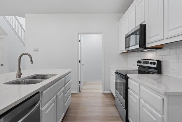 1816 Melissa Oaks Ln, Austin, TX 78744 - kitchen with appliances with stainless steel finishes, a sink, light wood-style flooring, tasteful backsplash, and white cabinetry