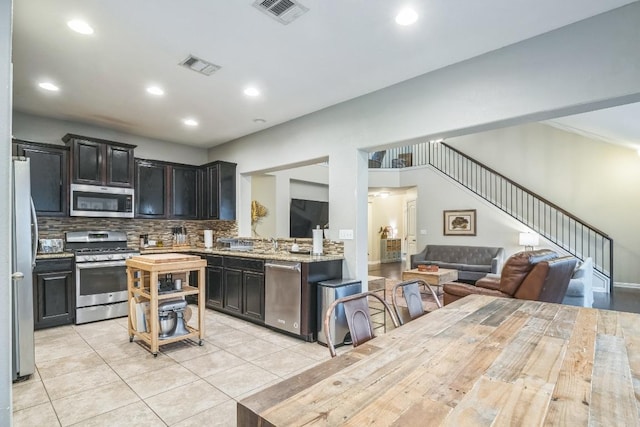 kitchen featuring stainless steel appliances, backsplash, light tile patterned floors, open floor plan, and recessed lighting
