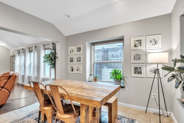 dining area featuring vaulted ceiling, light tile patterned floors, and baseboards