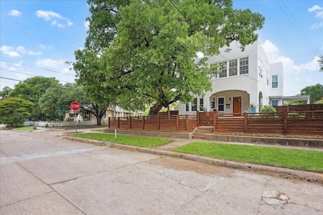 view of front facade featuring a fenced front yard, stucco siding, and a porch