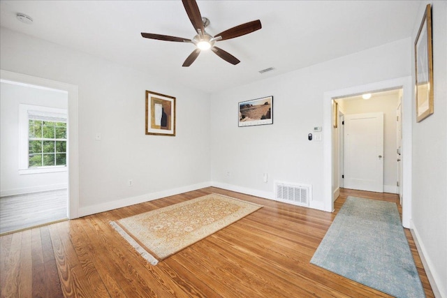unfurnished room featuring wood finished floors, ceiling fan, and baseboards