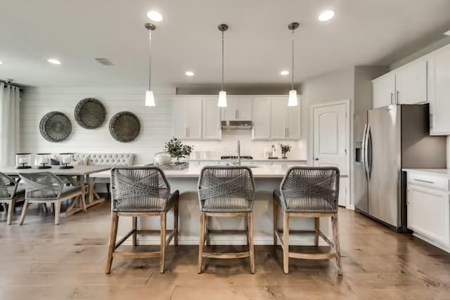 16804 Santiaguillo Trce, Manor, TX 78653 - kitchen with stainless steel refrigerator with ice dispenser, light countertops, an island with sink, a kitchen bar, and recessed lighting