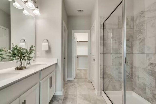 16804 Santiaguillo Trce, Manor, TX 78653 - bathroom with a shower stall, double vanity, baseboards, a walk in closet, and marble finish floors