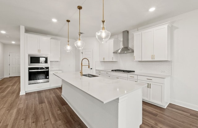 16804 Santiaguillo Trce, Manor, TX 78653 - kitchen with stainless steel appliances, wall chimney range hood, dark wood-style flooring, decorative backsplash, and light countertops