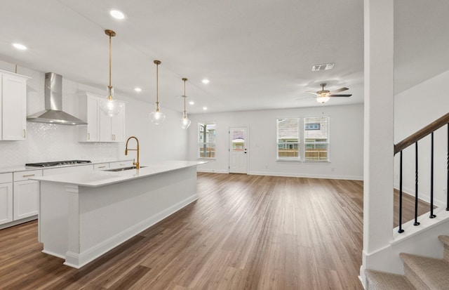 16804 Santiaguillo Trce, Manor, TX 78653 - kitchen with wall chimney range hood, wood finished floors, decorative backsplash, white cabinetry, and recessed lighting