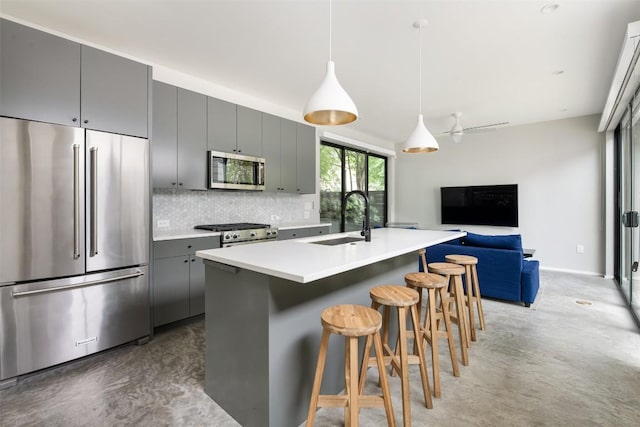 404 W Milton St, Austin, TX 78704 - kitchen featuring stainless steel appliances, a sink, gray cabinetry, decorative backsplash, and a breakfast bar