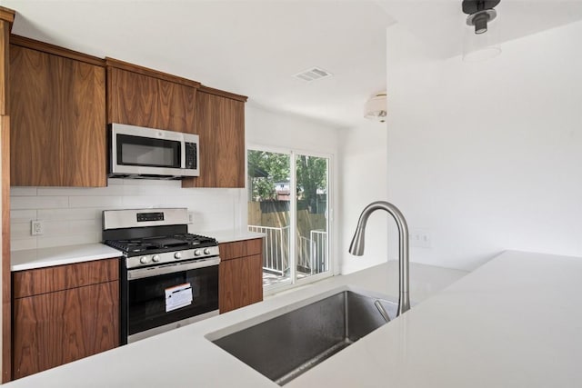 1800 Nicole Cir, Round Rock, TX 78664 - kitchen featuring stainless steel appliances, a sink, tasteful backsplash, light countertops, and brown cabinetry