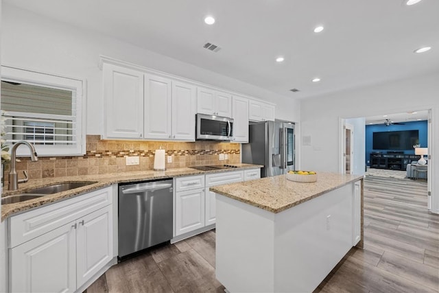 906 Texas Trl, Austin, TX 78737 - kitchen with stainless steel appliances, a sink, a center island, white cabinets, and recessed lighting