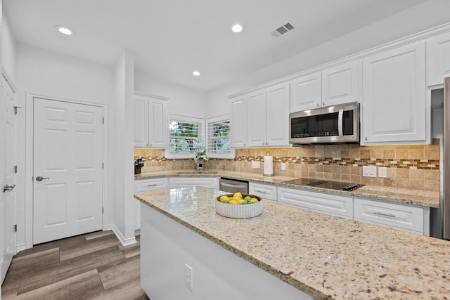 906 Texas Trl, Austin, TX 78737 - kitchen with stainless steel appliances, white cabinets, wood finished floors, a sink, and recessed lighting