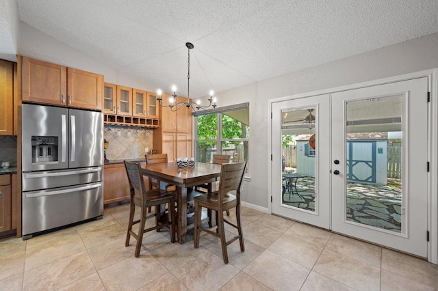 11707 Ruffed Grouse Dr, Austin, TX 78758 - dining room featuring a textured ceiling, a chandelier, french doors, vaulted ceiling, and light tile patterned floors