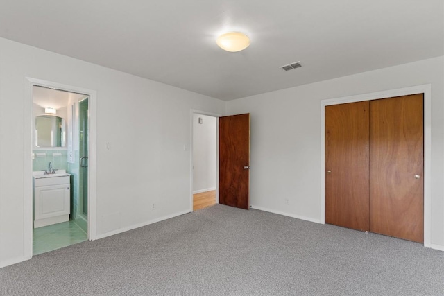 unfurnished bedroom featuring carpet floors, a sink, a closet, and baseboards