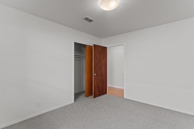 unfurnished bedroom with light colored carpet, a closet, and baseboards