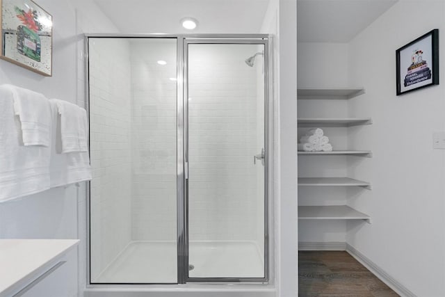 bathroom featuring wood finished floors, a shower stall, baseboards, vanity, and recessed lighting