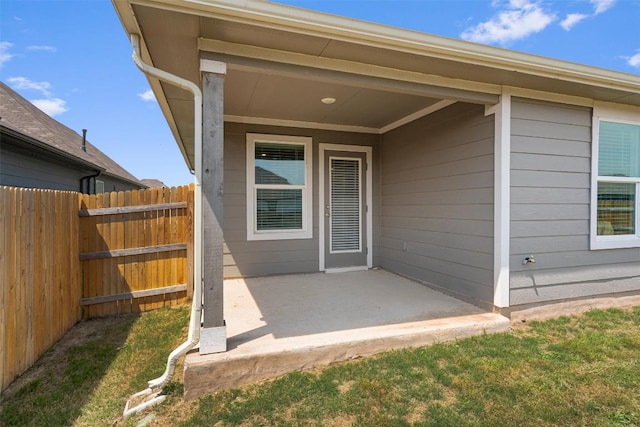 view of exterior entry featuring a patio and fence