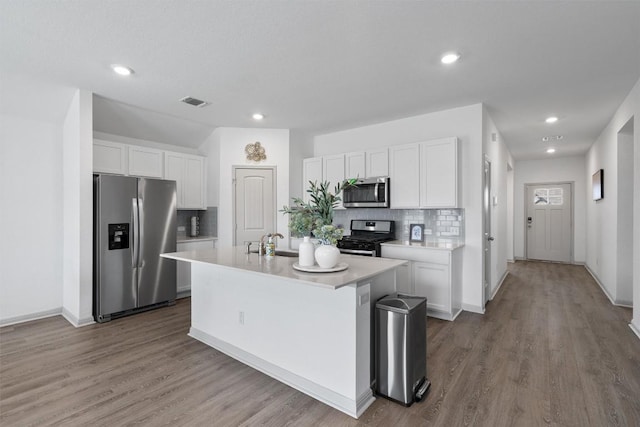 kitchen featuring stainless steel appliances, a sink, backsplash, white cabinets, and recessed lighting