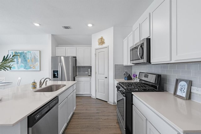 kitchen with appliances with stainless steel finishes, a sink, light countertops, white cabinets, and recessed lighting