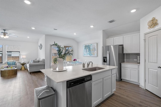 kitchen with appliances with stainless steel finishes, a sink, dark wood-style floors, an island with sink, and vaulted ceiling