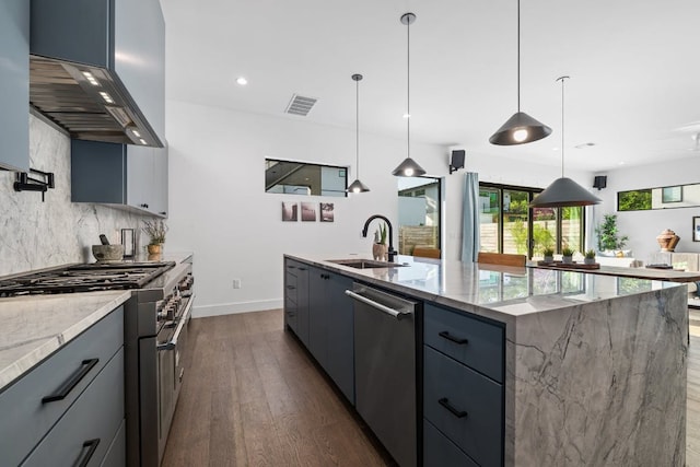 kitchen with appliances with stainless steel finishes, a sink, exhaust hood, dark wood finished floors, and backsplash
