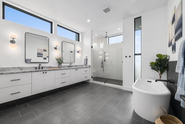 full bath with double vanity, a stall shower, a freestanding tub, tile patterned flooring, and recessed lighting